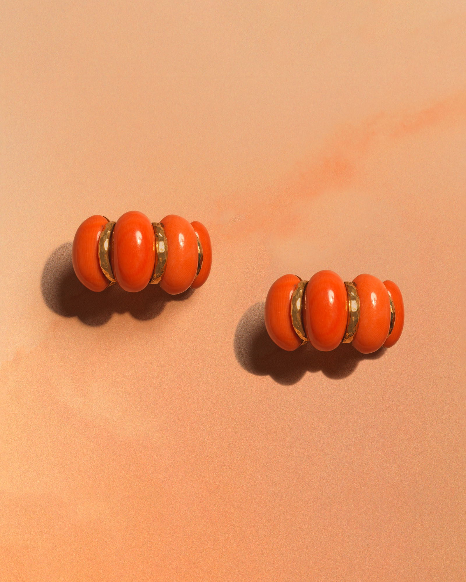 DAVID WEBB: CORAL EARCLIPS: DAVID WEBB: CORAL EARCLIPSOf bombé design, the half-hoop earclips comprising alternating coral corallium rubrum cabochons and hammered batons, signed Webb, length 3.1cmFootnotes:Jewellery from a