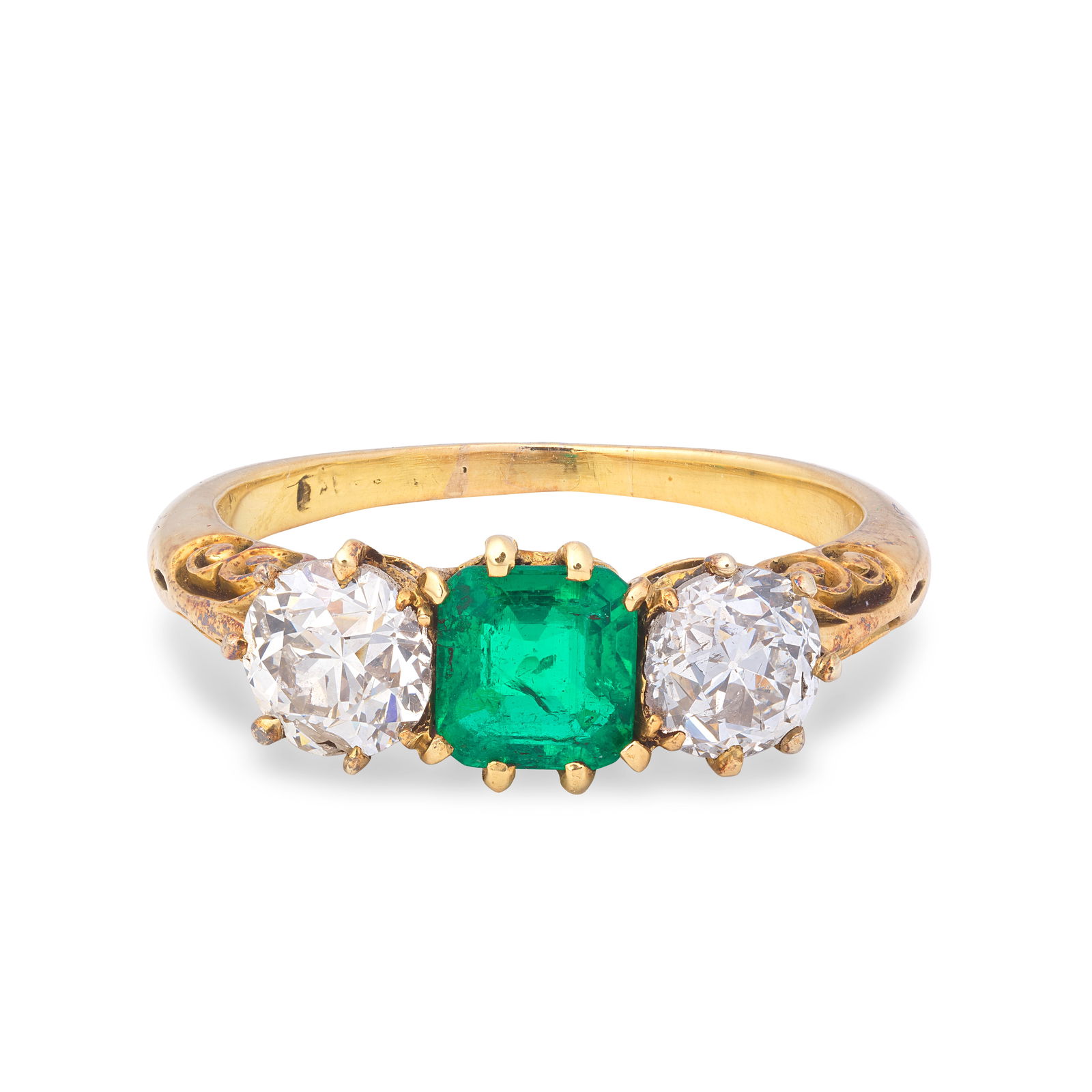 EMERALD AND DIAMOND THREE-STONE RING, CIRCA 1900: EMERALD AND DIAMOND THREE-STONE RING, CIRCA 1900The octagonal step-cut emerald between two old brilliant-cut diamonds, to a scrolled gallery, mounted in gold, diamond approx. 0.90ct total, ring size