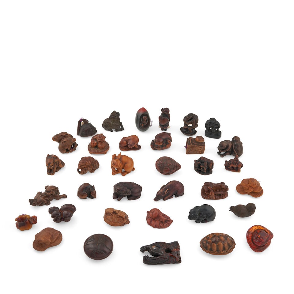 Thirty-five Wood, Amber, and Glass Netsuke Japan, (35): Thirty-five Wood, Amber, and Glass Netsuke Japan, arranged from top to bottom in rows, the first row from left to right comprising: a lotus pod, unsigned; a goat, unsigned; a monkey seated within a