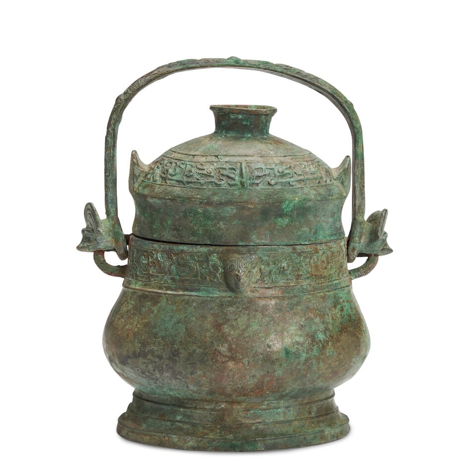 A Bronze Wine Vessel and Cover with Handle, You China, Western Zhou style,: A Bronze Wine Vessel and Cover with Handle, You China, Western Zhou style, 11 1/2in (29.2cm) high Lot to be sold without reserve. This lot is subject to the following lot symbols: ¤ ¤