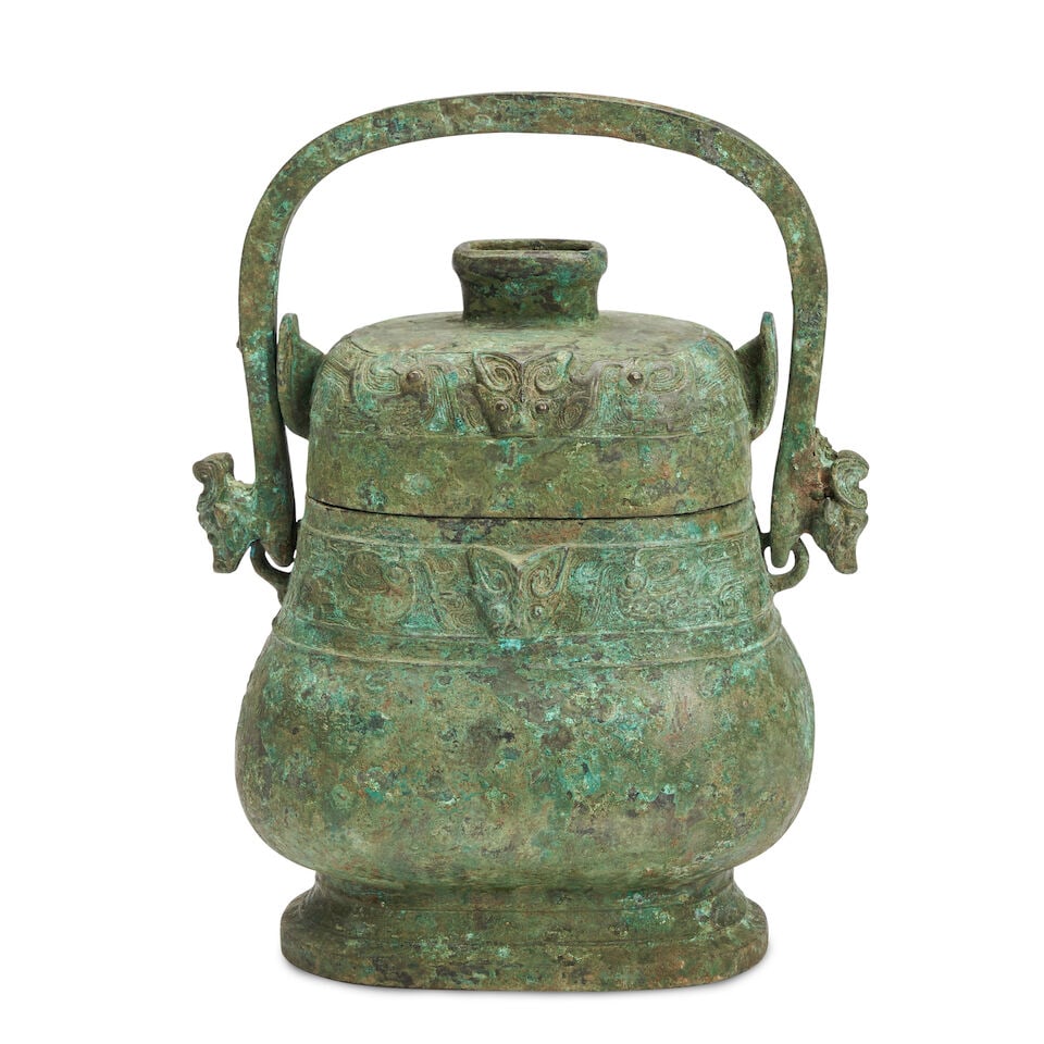 A Bronze Wine Vessel and Cover with Handle, You China, Western Zhou style: A Bronze Wine Vessel and Cover with Handle, You China, Western Zhou style 11 1/2in (29.2cm) high Lot to be sold without reserve. This lot is subject to the following lot symbols: ¤ ¤ Unless