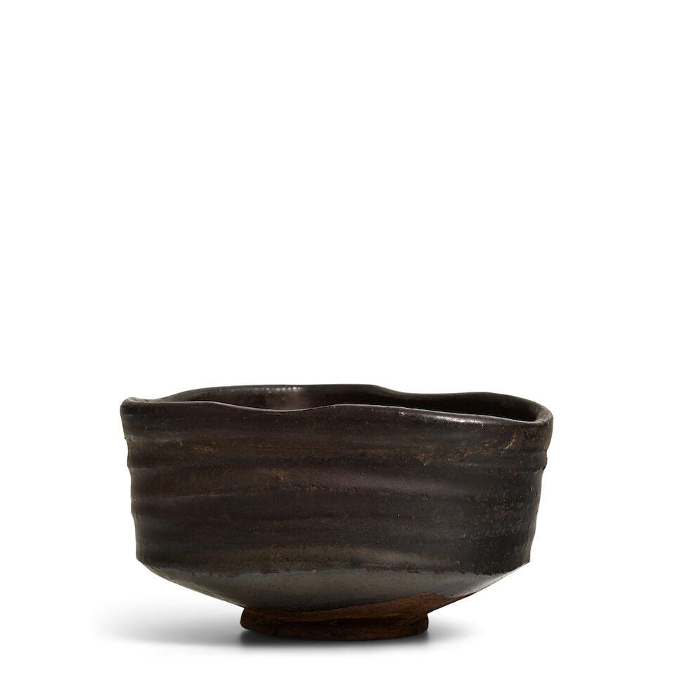 AN ORIBE-GURO CHAWAN (TEA BOWL) Edo period (1615-1868) or Meiji era (1868-1912), 19th century: AN ORIBE-GURO CHAWAN (TEA BOWL) Edo period (1615-1868) or Meiji era (1868-1912), 19th century The vessel in a kutsugata (shoe-shape) form, almost entirely coated in an iron-oxide black glaze, several