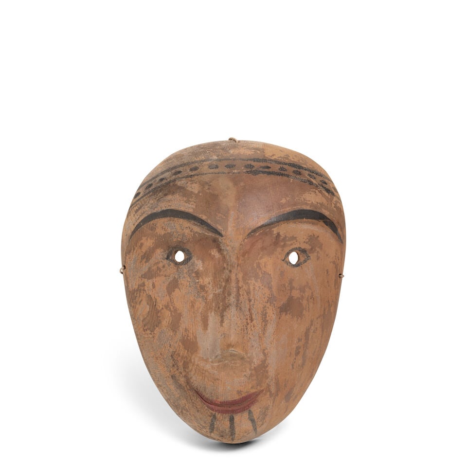 A Yup'ik mask: A Yup'ik mask Likely lower Kuskokwim region, AK, carved and partially painted in red and black, with petite features, pierced through the eyes and at three points around the edge. height 8 3/4in,