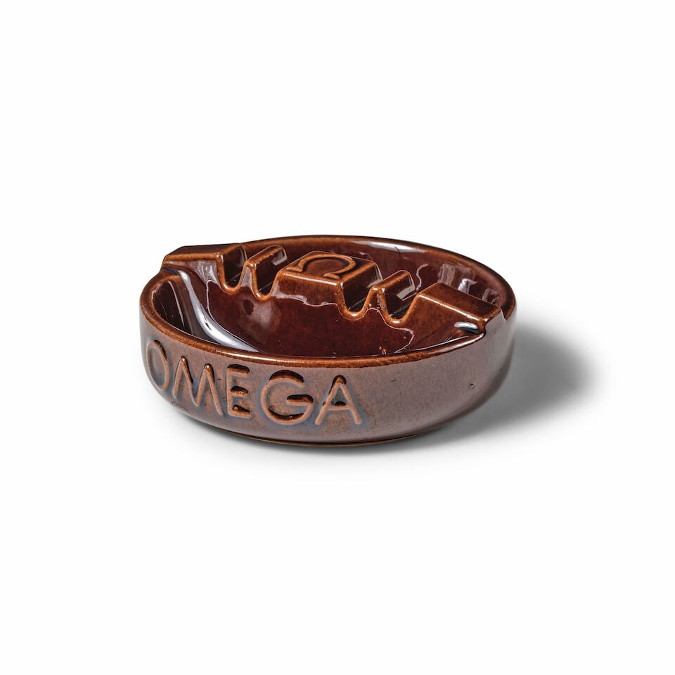 Omega. Round brown glazed ceramic ashtray Omega. Cendrier rond marron en ceramique émaill&...: Omega. Round brown glazed ceramic ashtray Omega. Cendrier rond marron en ceramique émaillé 12cm diameter Good condition This lot is subject to the following lot symbols: Ω Ω VAT