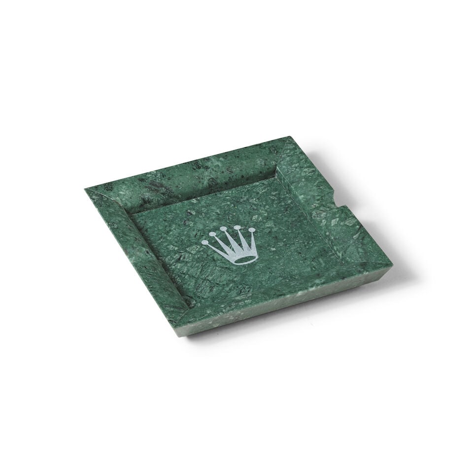 Rolex. A large green marble ashtray Rolex. Grand cendrier vert en marbre: Rolex. A large green marble ashtray Rolex. Grand cendrier vert en marbre 18.5cm x 18.5cm Two chipped corners This lot is subject to the following lot symbols: Ω Ω VAT on imported items at th
