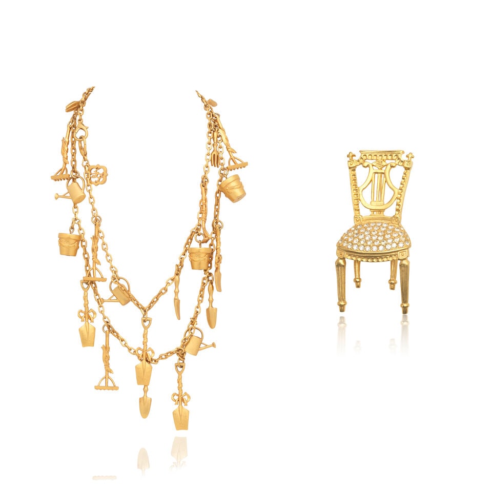 Karl Lagerfeld: Two Pieces of Costume Jewellery 1980s: Karl Lagerfeld: Two Pieces of Costume Jewellery 1980s To include a gilt metal 'Gardening Tools' long charm necklace, 60cm long, and a gilt metal and crystal chair brooch, 8cm high, (2) Condition Grade