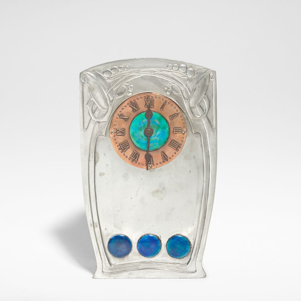 Archibald Knox Tudric clock, model no. 0369, circa 1905: Archibald Knox Tudric clock, model no. 0369, circa 1905 Pewter, copper and enamel, the copper chapter ring with raised Roman numerals. 19.5 cm high, 11.5 cm wide, 6.5 cm deep Stamped to base Tudric