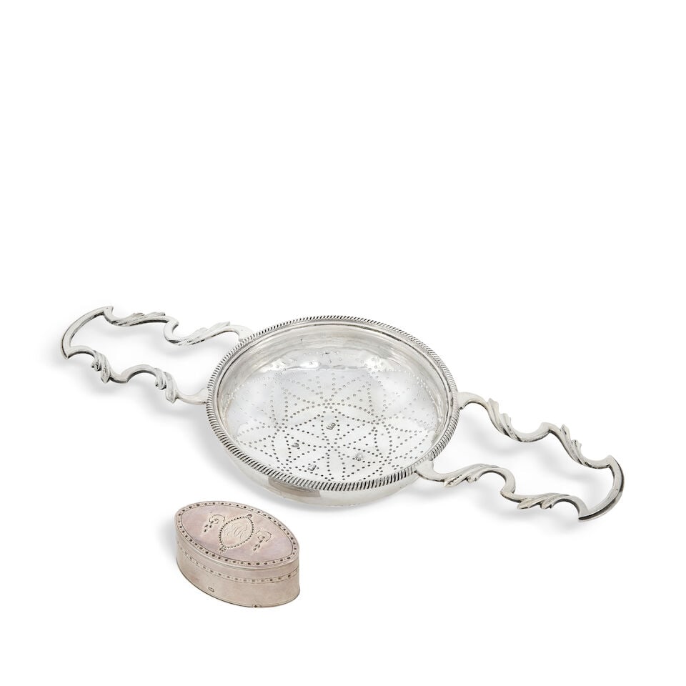A George III silver two-handled lemon strainer Samuel Herbert & Co, London 1767 (2): A George III silver two-handled lemon strainer Samuel Herbert & Co, London 1767 Circular bowl with gadroon rim, pierced dots to form a flower motif, elongated open-work scroll handles, length handle t