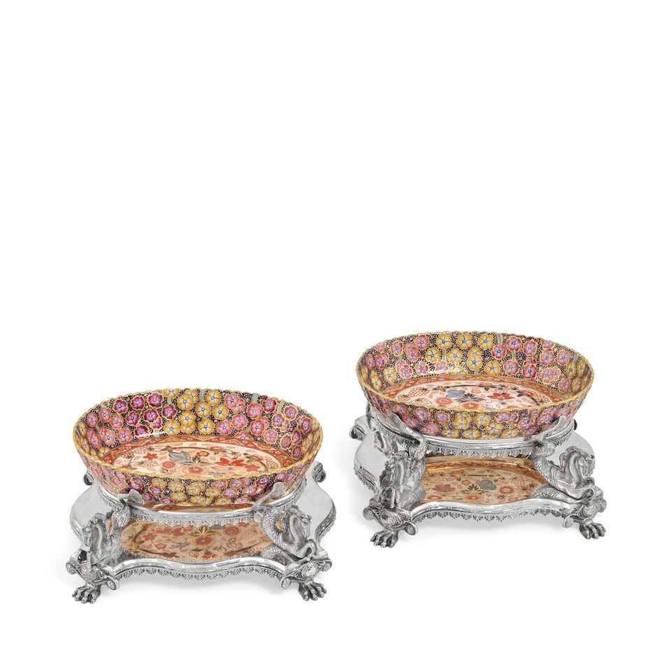 A pair of electroplated stands, with ceramic dishes Walker & Hall, late 19th / early 20th centur...: A pair of electroplated stands, with ceramic dishes Walker & Hall, late 19th / early 20th century Shaped-rectangular base with anthemion lower gallery, paw feet to each corner, the central oval receiv