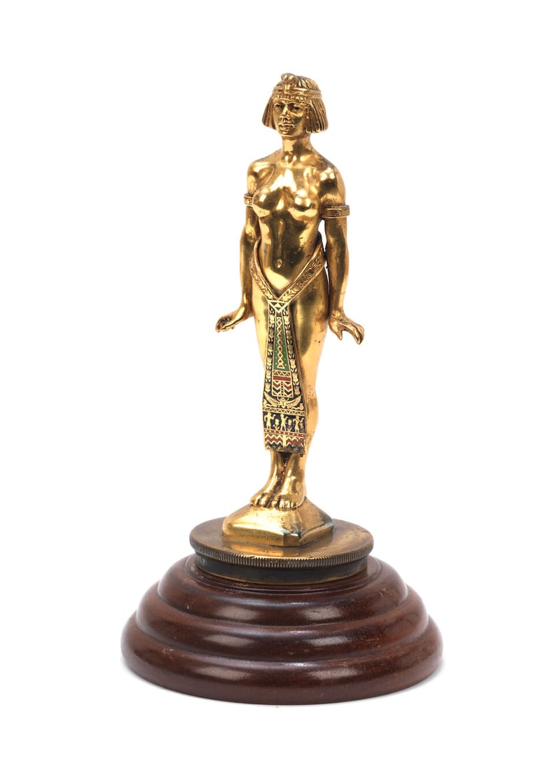 An 'Egyptienne' mascot, 1920s,: An 'Egyptienne' mascot, 1920s, stamped 'B'ham Medal Co. Birmingham' to rear of base, and 'Copyright' to front of base, cast bronze mascot with gilt finish depicting a standing Egyptian female nude wit