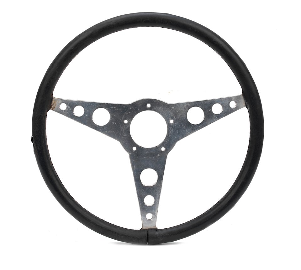 An OSCA MT4 1954 Mille Miglia steering wheel,: An OSCA MT4 1954 Mille Miglia steering wheel, three-spoke wheel with black leather stitched grip, race-used with some wear, marks and tear to leather, 34cm outside diameter, offered with copied image