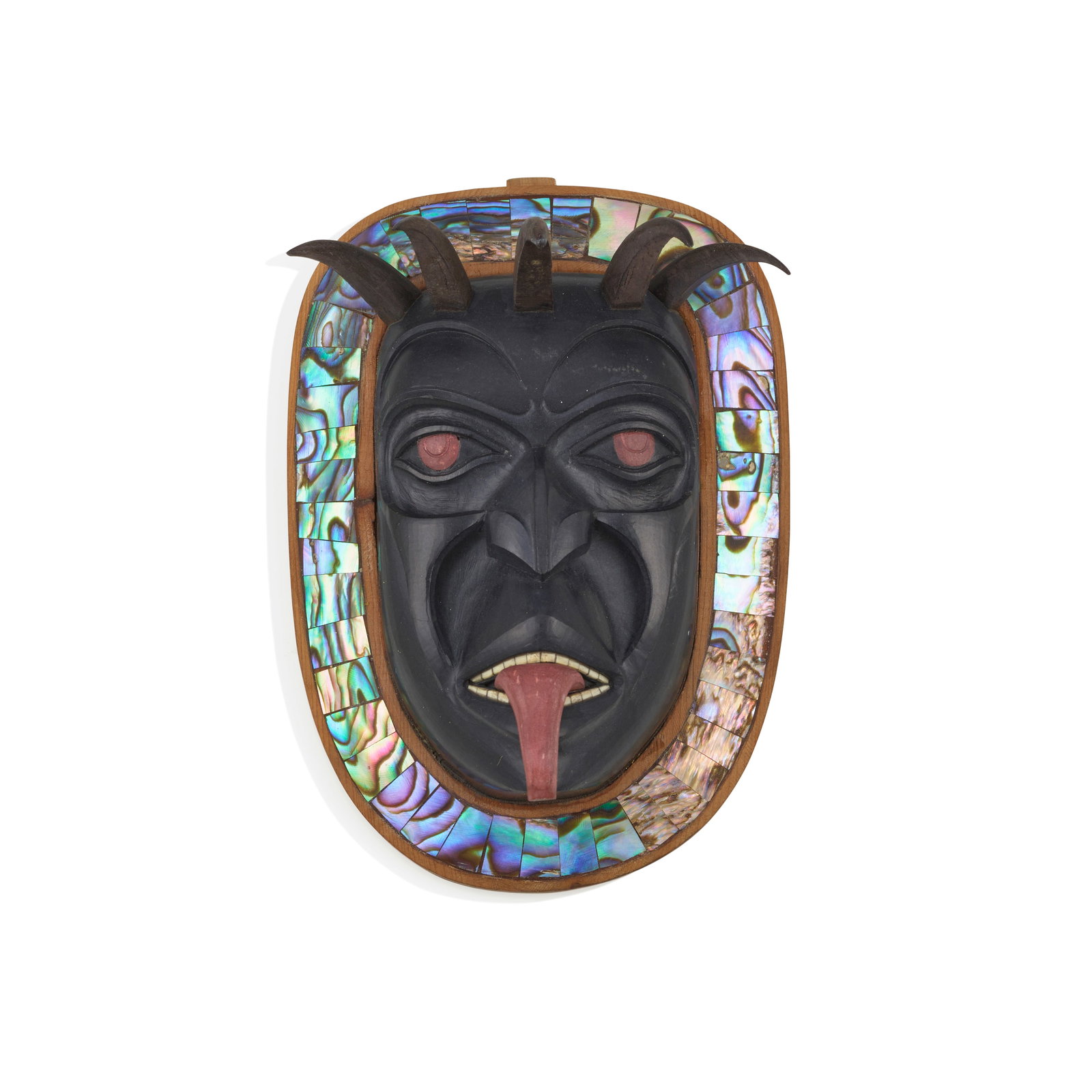 A Marcel Russ carved argillite, catlinite, and wood amulet: Marcel Russ Haida, (b. 1973), a carved argillite pendant with catlinite and wood accents and framed within a wood and inlaid surround, depicting the face of a crowned shaman with lolling tongue, signe