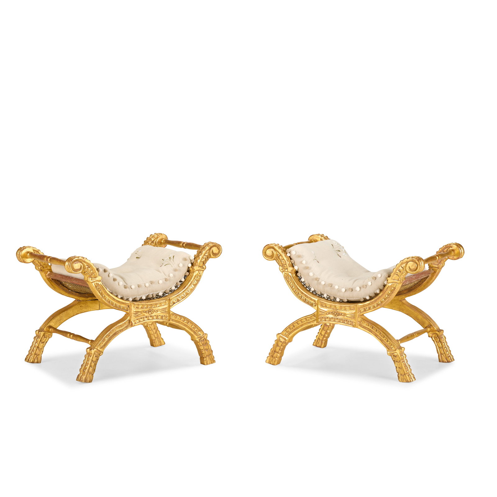 A pair of carved giltwood window seatsSecond half 19th century (2): A pair of carved giltwood window seats Second half 19th century Of scrolled x-shaped curule design, with caned seat and recently upholstered shaped squab cushions, 73cm wide x 49.5cm deep x 55cm high,