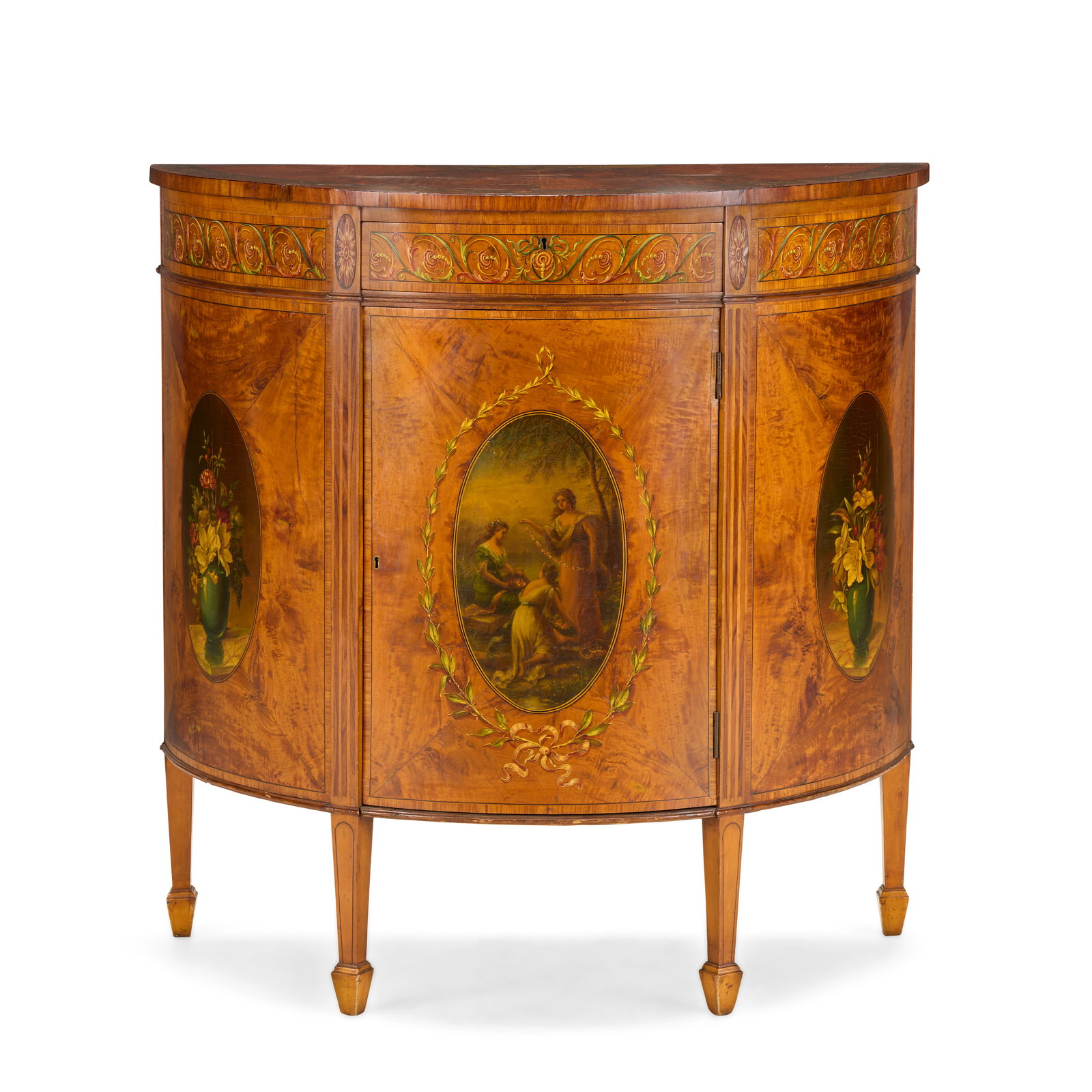 An Edwardian satinwood and polychrome decorated demi-lune side cabinetEarly 20th century, in the...: An Edwardian satinwood and polychrome decorated demi-lune side cabinet Early 20th century, in the George III style The radiating veneered top painted with a floral border above a frieze drawer and cen