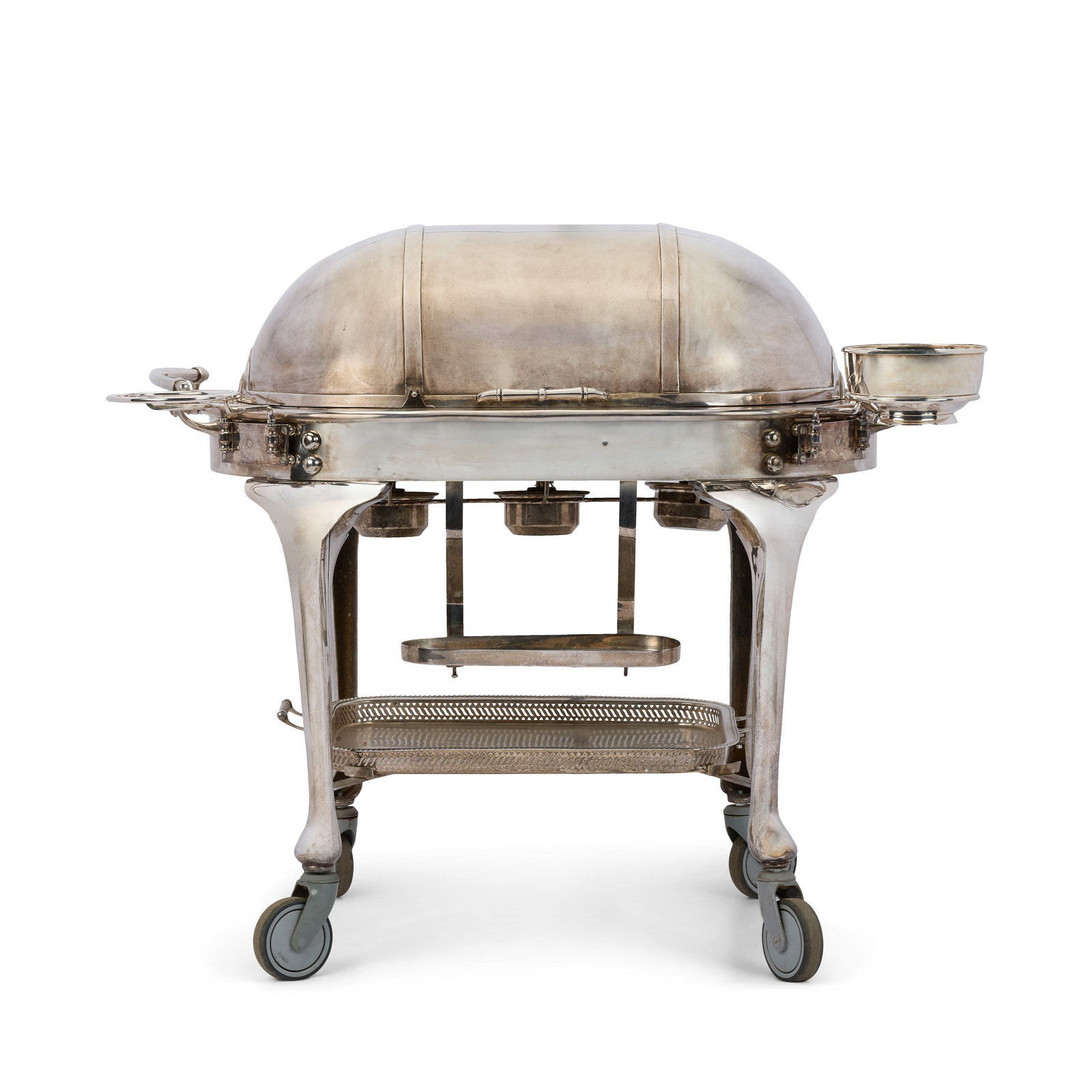 An early 20th century silver plated carving trolleyJames Deakin & Sons, Sheffield: An early 20th century silver plated carving trolley James Deakin & Sons, Sheffield The domed roll-back cover enclosing a warming plate over bain-marie, three circular recesses, with a utensil tray and
