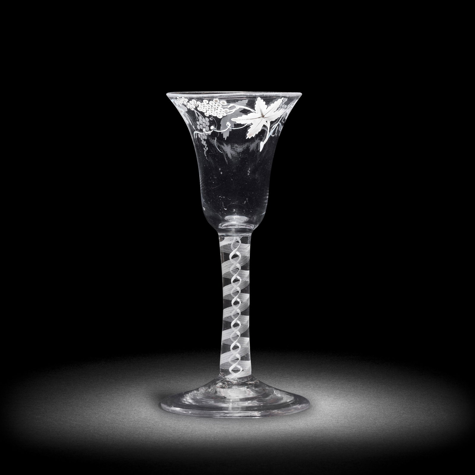 A Beilby enamelled opaque twist wine glass, circa 1765: A Beilby enamelled opaque twist wine glass, circa 1765 The bell bowl painted in opaque white with a border of fruiting vine, the rim with traces of gilding, on a double-series stem containing a sixtee