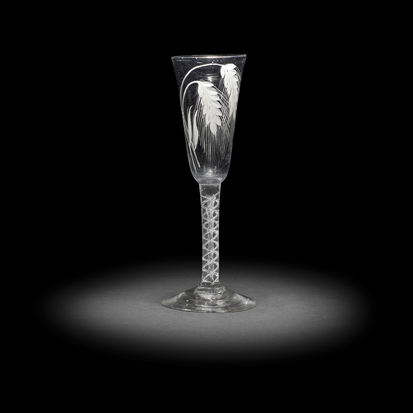 A rare wash-enamelled airtwist ale glass, circa 1750-60: A rare wash-enamelled airtwist ale glass, circa 1750-60 The tall round funnel bowl painted in a pale grey enamel with four crossed ears of barley filling the entire bowl, the details picked out in dar