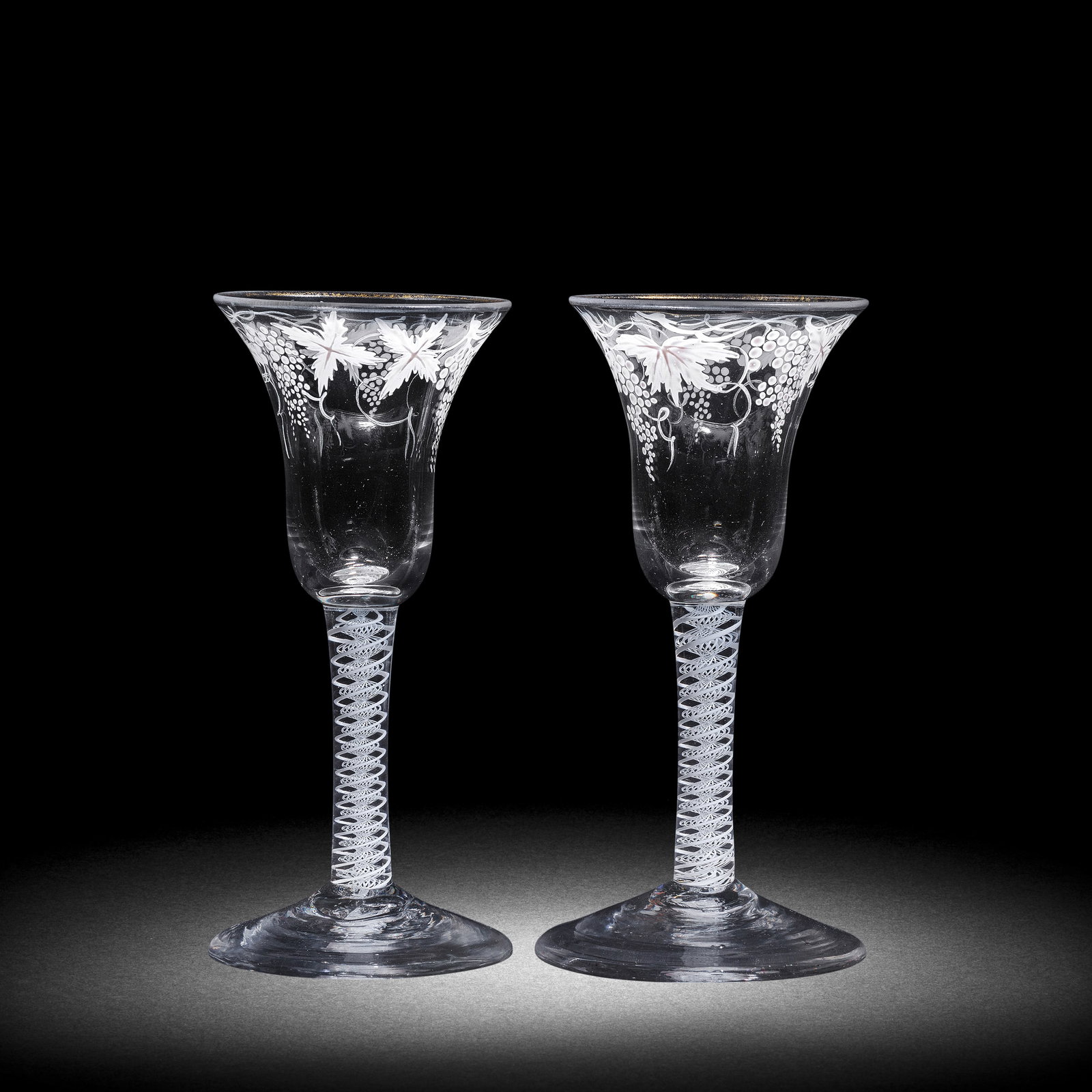 A matched pair of Beilby enamelled opaque twist wine glasses, circa 1765: A matched pair of Beilby enamelled opaque twist wine glasses, circa 1765 The bell bowls painted in opaque white with continuous branches of fruiting vine, the rims with traces of gilding, on double-se