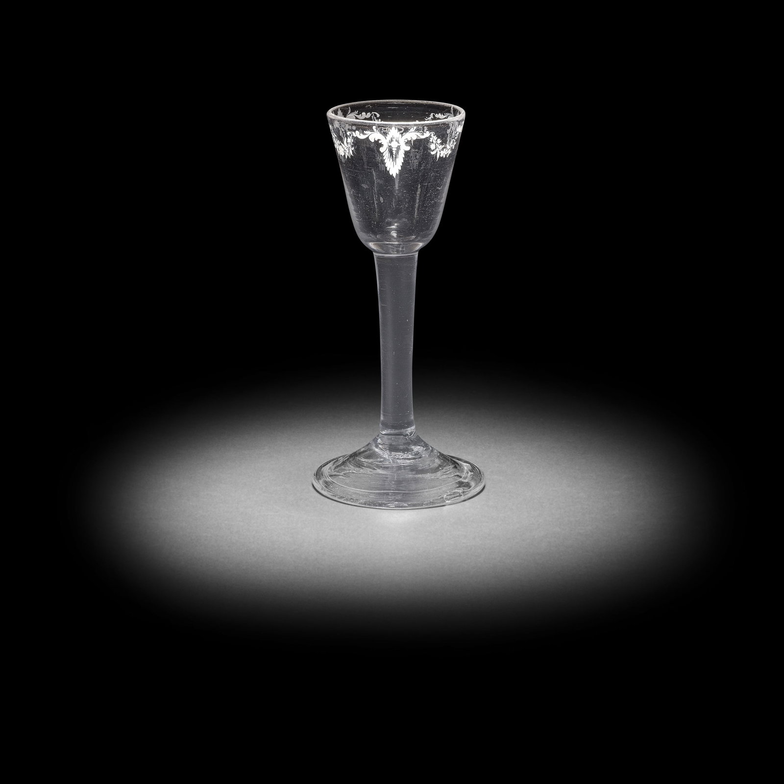 A very rare Beilby enamelled plain stem wine glass with floral garlands, circa 1765: A very rare Beilby enamelled plain stem wine glass with floral garlands, circa 1765 The round funnel bowl finely painted in opaque white with garlands of flowers hung from three scroll ornaments, fain