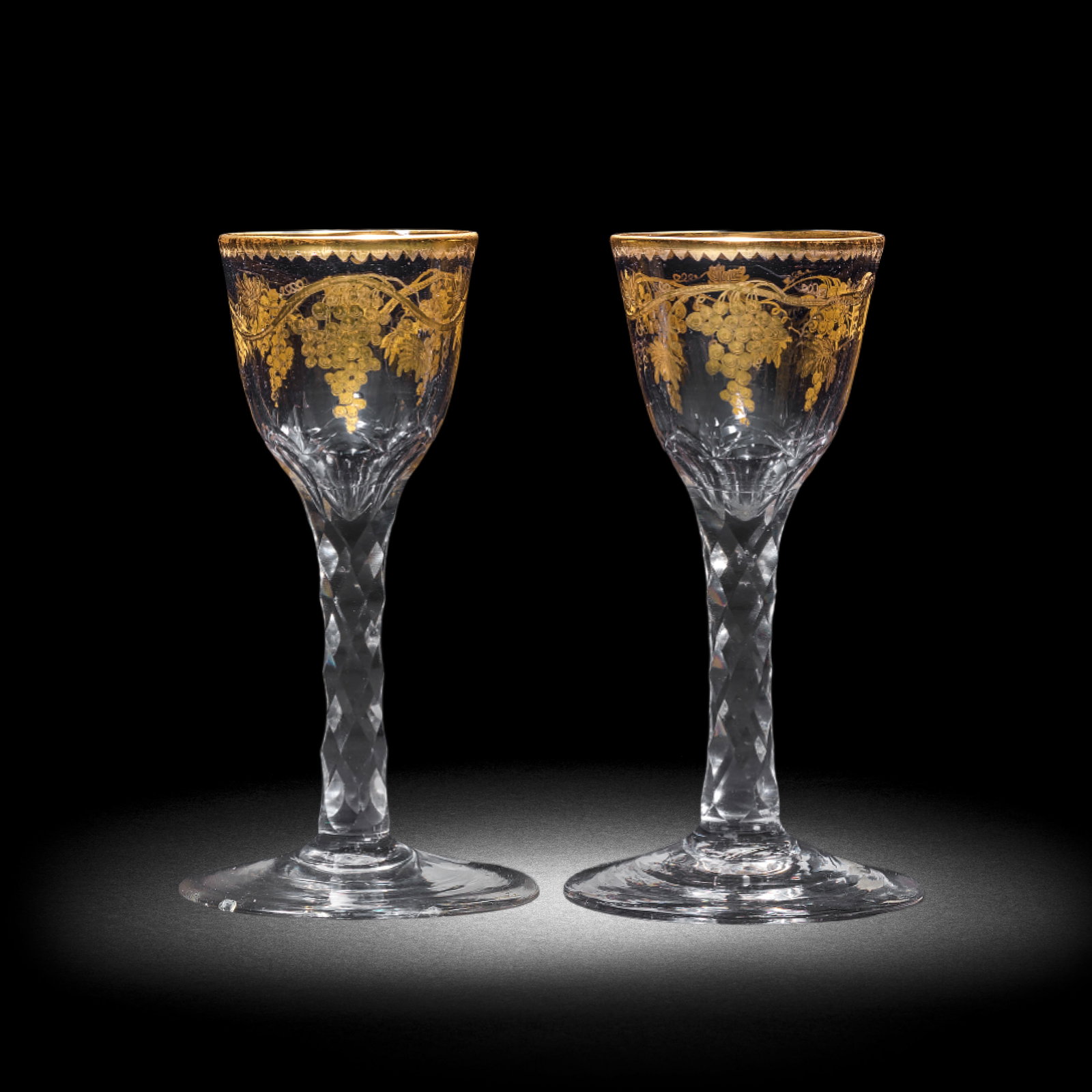 A matched pair of Giles gilded facet stem wine glasses, circa 1765-70: A matched pair of Giles gilded facet stem wine glasses, circa 1765-70 Decorated in the London workshop of James Giles, the ogee bowls painted in gold with meandering branches of fruiting vine, with gi