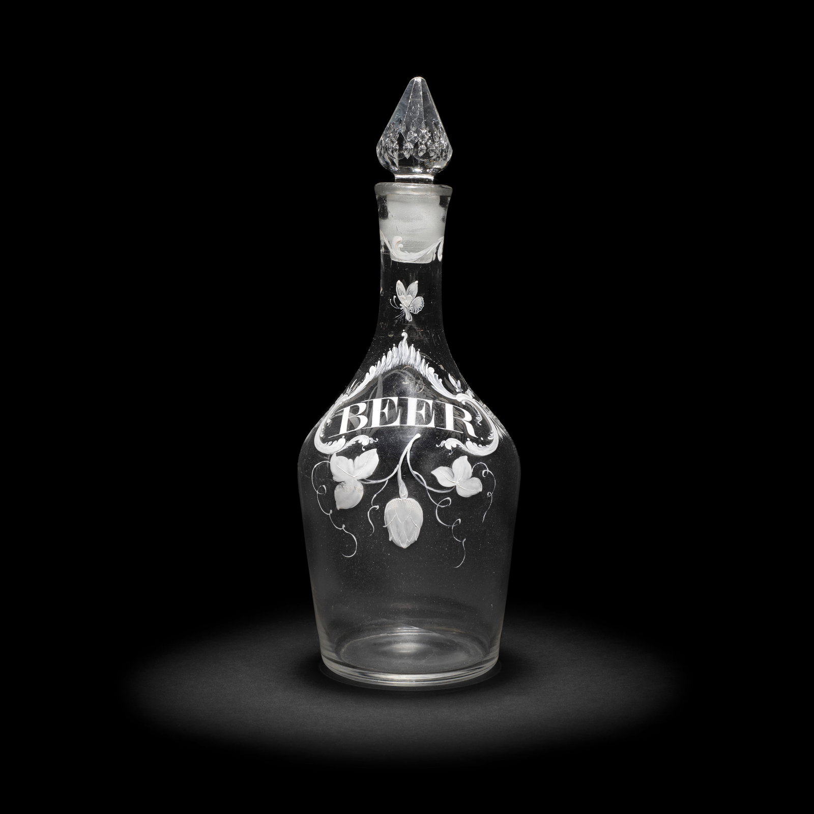 A rare Beilby enamelled Beer decanter and a stopper, circa 1765: A rare Beilby enamelled Beer decanter and a stopper, circa 1765 Of shouldered form, painted in opaque white with a foliate and acanthus cartouche inscribed 'BEER' and suspended from a chain around the