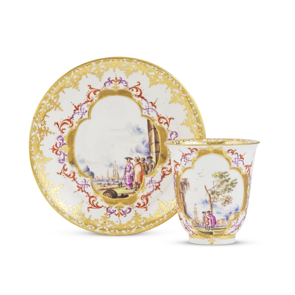 Gobelet et soucoupe en porcelaine de Meissen, vers 1730 A Meissen beaker and saucer, circa 1730: Gobelet et soucoupe en porcelaine de Meissen, vers 1730 A Meissen beaker and saucer, circa 1730 Each painted with a landscape scene within a gilt quatrelobe cartouche edged with iron-red and purple sc