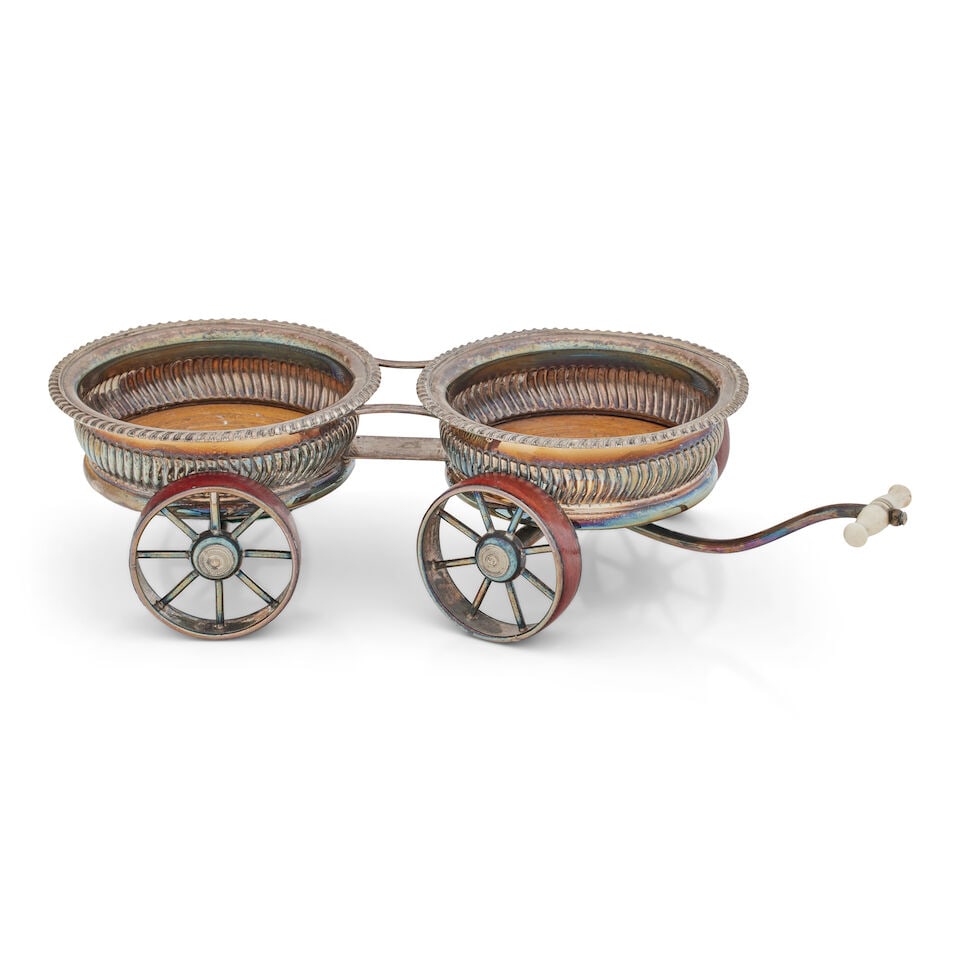 A Regency Sheffield plate decanter carriage circa 1820: A Regency Sheffield plate decanter carriage circa 1820 On four spoked wheels with red Morocco leather rims, the coasters with lobed sides and gadrooned rims with turned wood bases, the shaft with turn