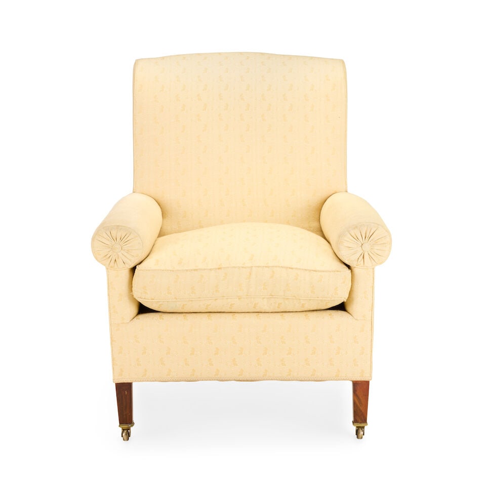 A Victorian easy upholstered armchair Second half 19th century: A Victorian easy upholstered armchair Second half 19th century The rectangular back and seat with cylindrical bolster shaped arm rests, on tapered square front legs and splayed rear legs with brass