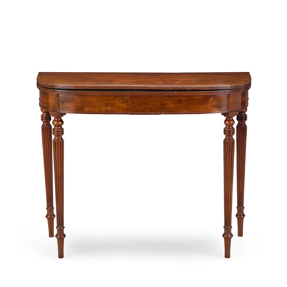 A Regency mahogany card tableEarly 19th century, in the manner of Gillows: A Regency mahogany card table Early 19th century, in the manner of Gillows The hinged D-shaped top enclosing a baize lined interior on turned and reeded tapering legs, 91cm wide x 44.5cm deep x 73cm