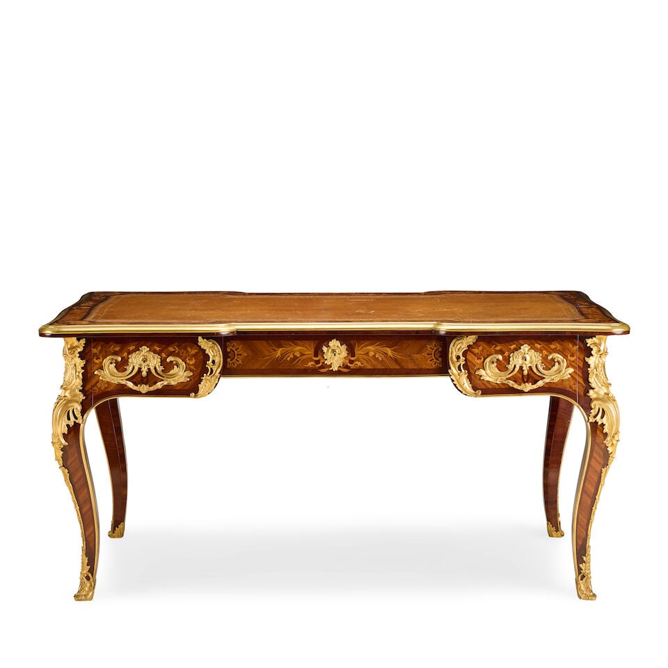 A French kingwood, purplewood, fruitwood marquetry and gilt bronze mounted bureau platEarly 20th...: A French kingwood, purplewood, fruitwood marquetry and gilt bronze mounted bureau plat Early 20th century in the Louis XV style The shaped top inset with a gilt tooled leather writing surface within a