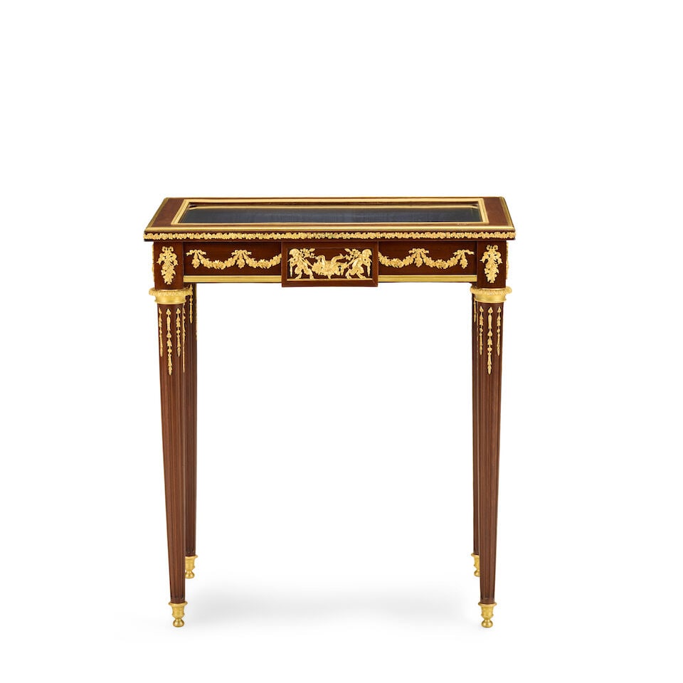 A French mahogany and gilt bronze mounted bijouterie tableFirst half 20th century in the Louis X...: A French mahogany and gilt bronze mounted bijouterie table First half 20th century in the Louis XVI style, in the manner of François Linke (1855-1946) The bevelled glazed hinged top enclosing a w