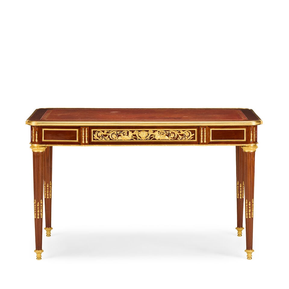 A French plum pudding mahogany, mahogany and gilt bronze mounted bureau platLate 19th century in...: A French plum pudding mahogany, mahogany and gilt bronze mounted bureau plat Late 19th century in the Louis XVI style, probably by Frédéric Schmit (1830-1880) The rectangular gilt tooled lea
