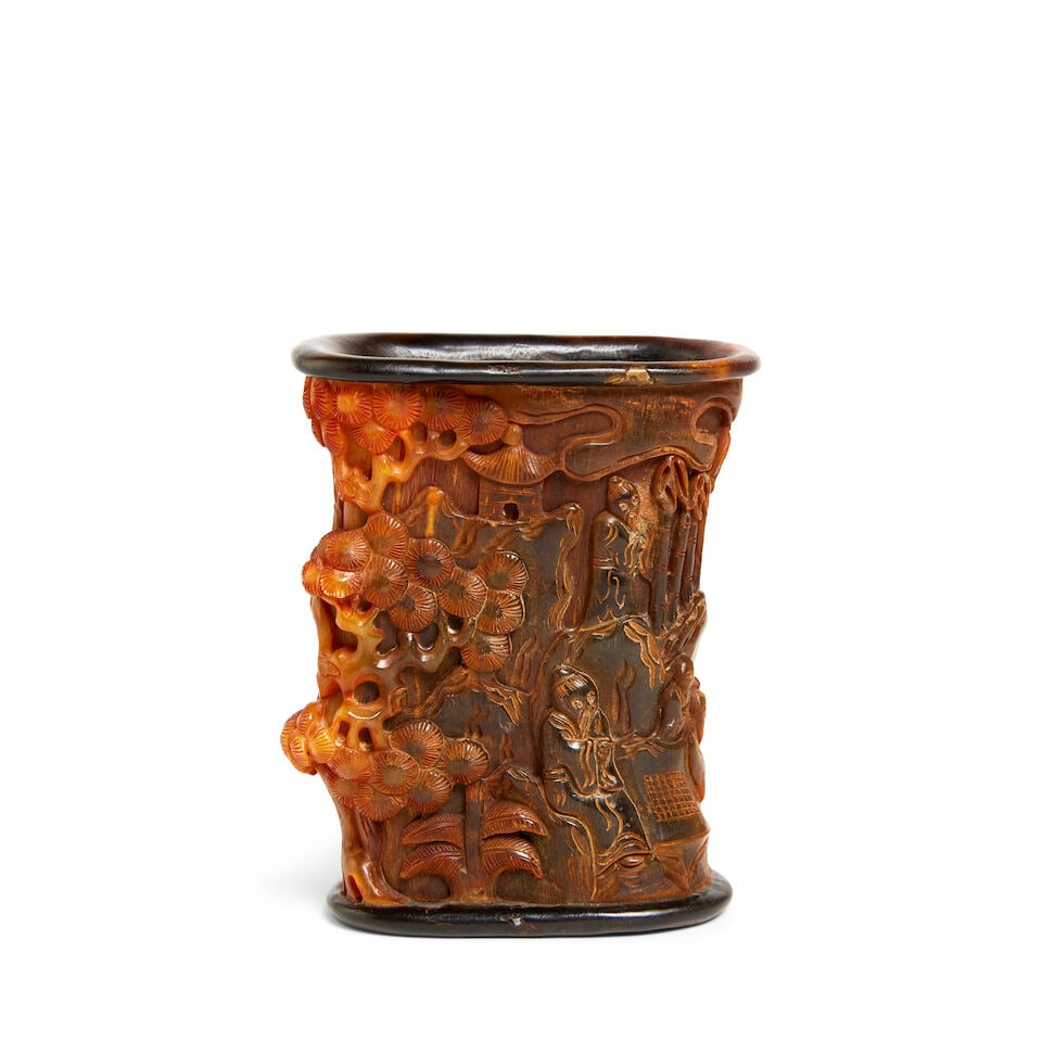 A buffalo horn brush pot 18th/19th century: A buffalo horn brush pot 18th/19th century Of irregular cylindrical form, the exterior carved in relief with a continuous panoramic landscape, depicting scholars engaging in various leisure pursuits, 