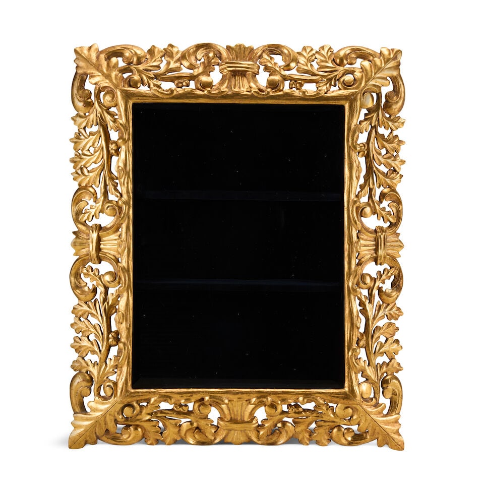 A carved giltwood wall mounted display cabinet Late 19th century and later: A carved giltwood wall mounted display cabinet Late 19th century and later The hinged door adapted from an Italian giltwood frame mounted with bevelled glass opening to enclose a velvet lined shelved 
