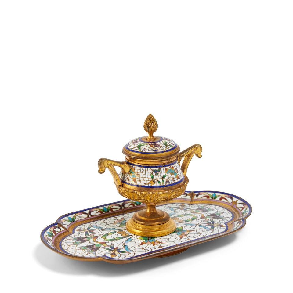 A French champlevé enamel and gilt bronze inkwell Late 19th / early 20th century: A French champlevé enamel and gilt bronze inkwell Late 19th / early 20th century The twin handled urn shaped inkwell with a hinged lid surmounted by a pineapple on a shaped tray and circular foot