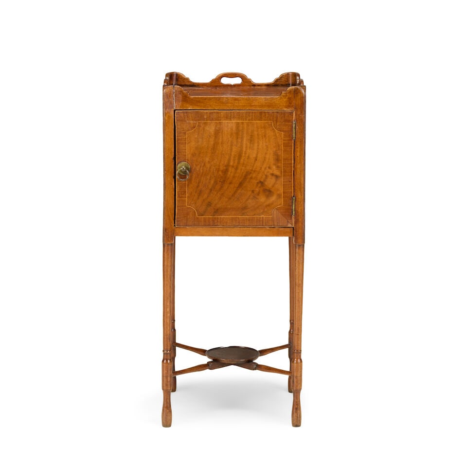 A George III mahogany tray top bedside cupboard Early 19th century: A George III mahogany tray top bedside cupboard Early 19th century With a single panelled door enclosing a void interior on turned supports united by an X-stretcher centred by a dished water jug