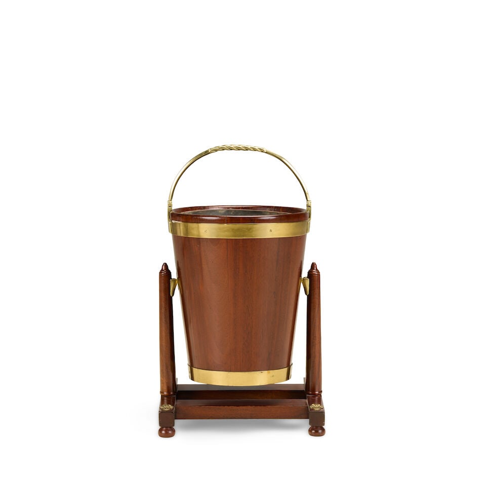 An Irish mahogany and brass bound peat bucket and standEarly 20th century by James Hicks, Dublin...: An Irish mahogany and brass bound peat bucket and stand Early 20th century by James Hicks, Dublin Of typical tapering form with a tôle liner together with a turned easel stand, labelled 'JAMES