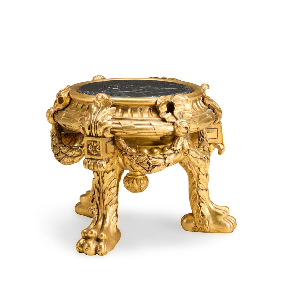 A French carved giltwood vase or urn stand Late 19th century: A French carved giltwood vase or urn stand Late 19th century The later associated marble top above a fluted frieze and a lobed body enclosed by olive leaf and berry ribbon-tied swags on acanthus leaf