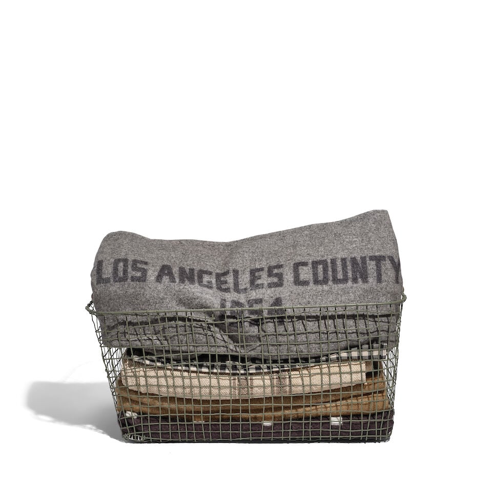 A CURATED BASKET OF BLANKETS AND TEXTILES: A CURATED BASKET OF BLANKETS AND TEXTILES Including one blanket inscribed LOS ANGELES COUNTY / 1954. overall approximately height 18in; width 26in; depth 17in Footnotes: From Diane Keaton's kitchen