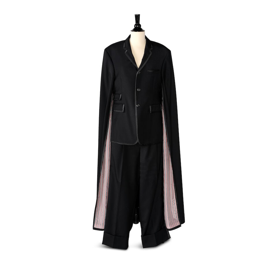A CUSTOM THOM BROWNE BLACK TUXEDO ENSEMBLE 2020: A CUSTOM THOM BROWNE BLACK TUXEDO ENSEMBLE 2020 Comprising a Chesterfield cape and a pair of adjustable cuffed tuxedo pants. (2) both marked size 2 This lot is subject to the following lot symbols: &#