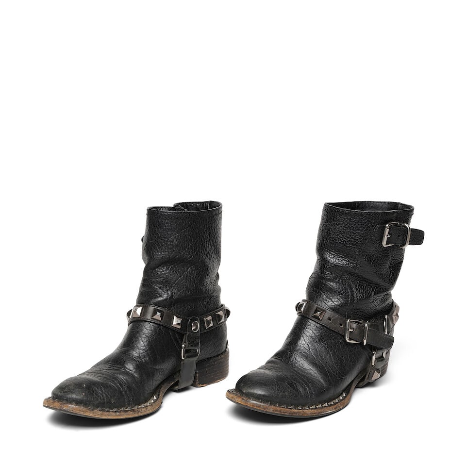 A PAIR OF MIU MIU BLACK LEATHER STUDDED HARNESS BIKER ANKLE BOOTS: A PAIR OF MIU MIU BLACK LEATHER STUDDED HARNESS BIKER ANKLE BOOTS No marked size. length 11 1/4in Footnotes: Literature Keaton, Diane. Fashion First. Rizzoli, New York, 2024. Worn on the cover of