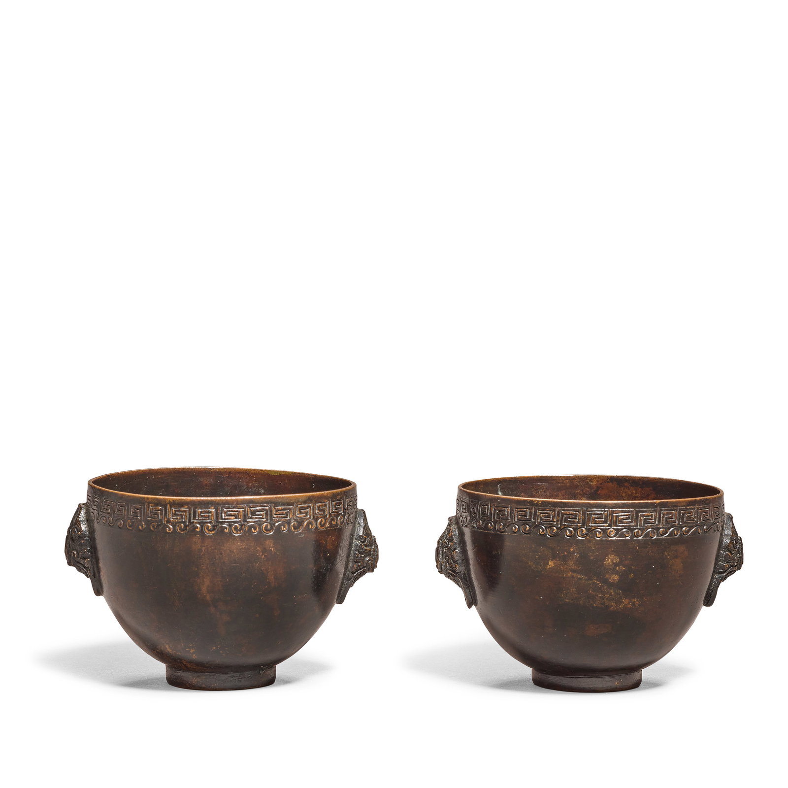 A PAIR OF BRONZE WINE CUPS 17th/18th century (4): A PAIR OF BRONZE WINE CUPS 17th/18th century Each resting on a short foot, cast with a pair of stylised cicada handles, with incised bands of key fret and scroll motifs beneath the rim, patinated to a