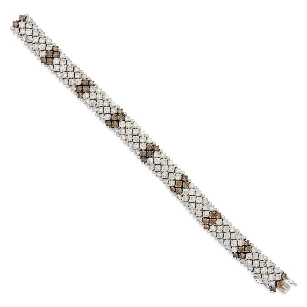 AN 18K WHITE GOLD, COLORED DIAMOND, AND DIAMOND BRACELET: AN 18K WHITE GOLD, COLORED DIAMOND, AND DIAMOND BRACELET Set with full-cut diamonds, total weight 14.01 carats, and brown diamonds, total weight 3.08 carats, weight 38.4 dwt, length 6 5/8 in. For furt