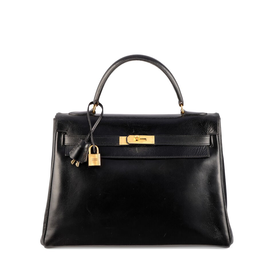 Hermès: a Black Box Leather Retourne Kelly 32 1960s (includes care booklet and dust bags): Hermès: a Black Box Leather Retourne Kelly 32 1960s Gold tone hardware Condition Grade C 32cm wide, 22cm high, 12.5cm deep, 9.5cm handle drop, includes care booklet and dust bags For further