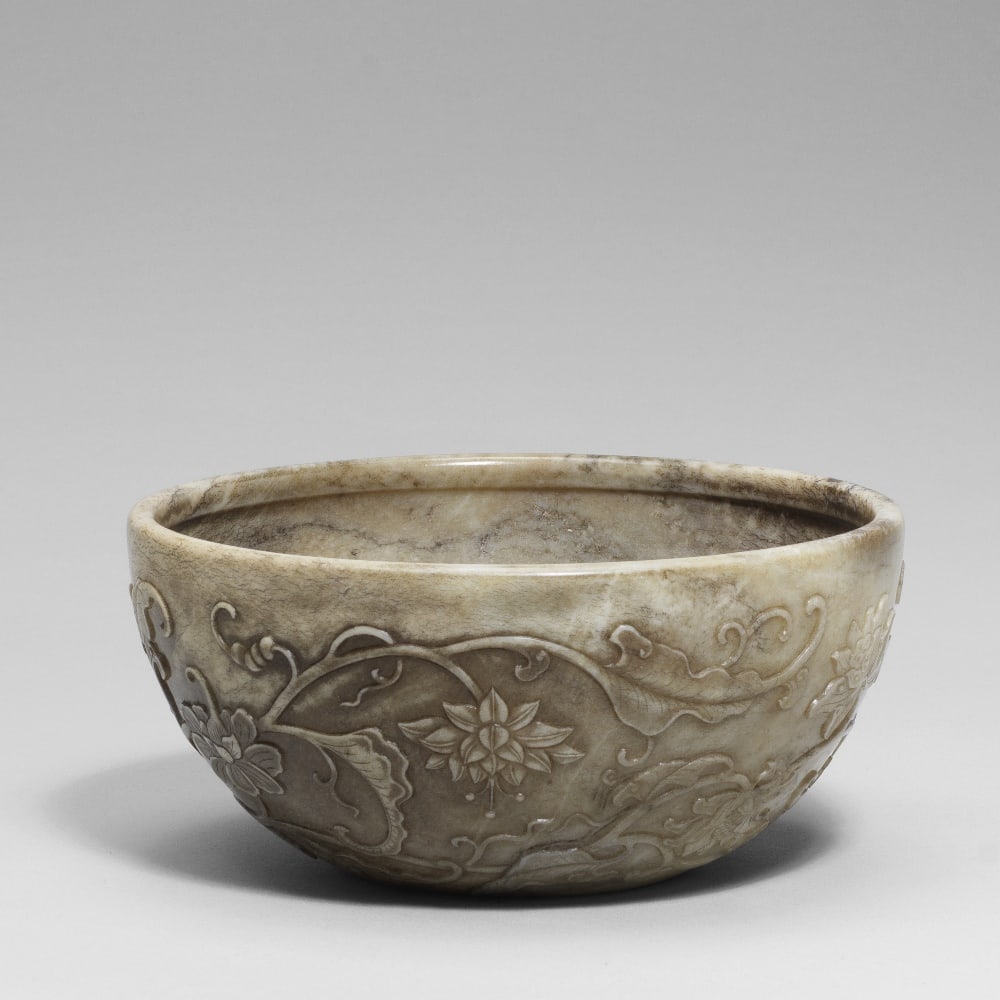 A RARE 'CHICKEN BONE' JADE CARVED BOWL 18th century (2): A RARE 'CHICKEN BONE' JADE CARVED BOWL 18th century Crisply carved in relief to the exterior with blooming flower heads including lotuses on a continuous undulating leafy branch, the interior carved i