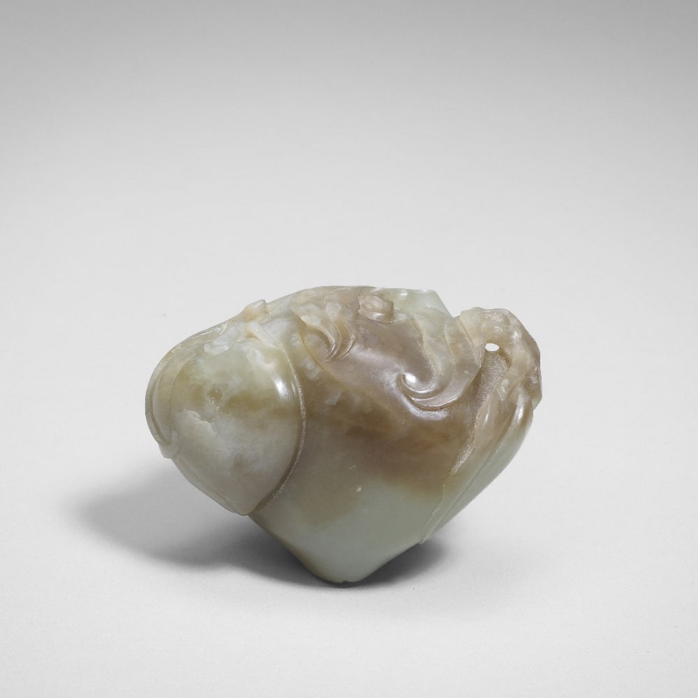 A PALE GREEN AND CHESTNUT BROWN JADE 'PEACHES AND BAT' CARVING 18th century: A PALE GREEN AND CHESTNUT BROWN JADE 'PEACHES AND BAT' CARVING 18th century The pebble smoothly carved as a large ripe peach beside a smaller peach issuing from gnarled leafy stems, a small auspicious