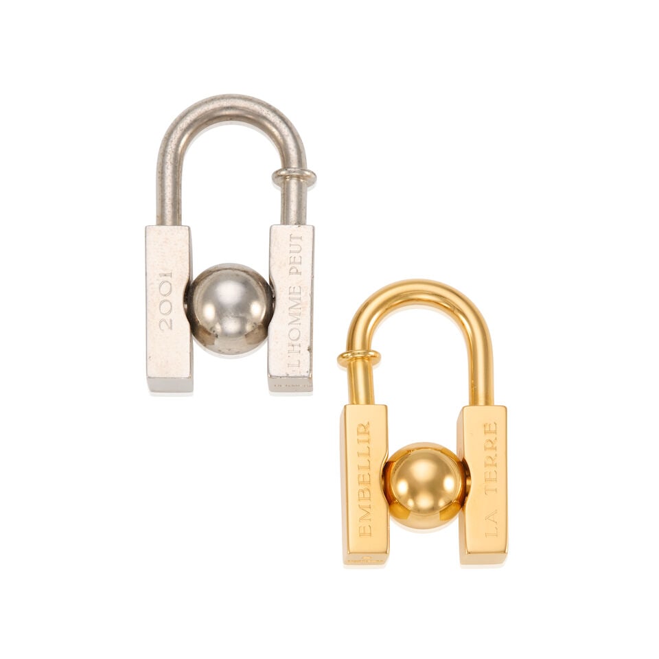 HERMÈS: A SET OF TWO L'HOMME PEUT EMBELLIR LA TERRE CADENA LOCK CHARM 2001: HERMÈS: A SET OF TWO L'HOMME PEUT EMBELLIR LA TERRE CADENA LOCK CHARM 2001 • Gold and Palladium Plated Hardware with Rotating Globe Detail • Spring-Loaded Push Lock Closure •