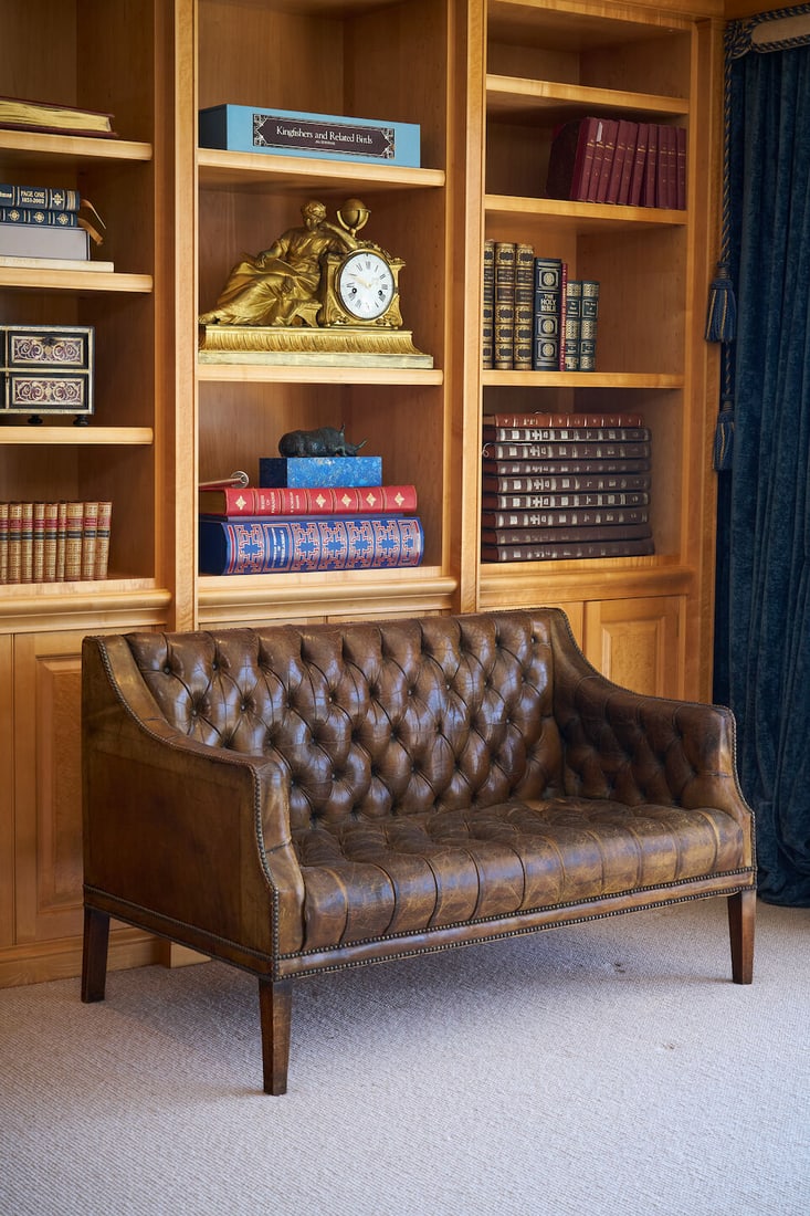 A Library two seater leather sofa, likely modern,: A Library two seater leather sofa, likely modern, with deep button back leather in faded green with tufted seat and back, brass studding, height: 81.0cm, 134.0cm, depth: 80.0cm This lot is subject to 
