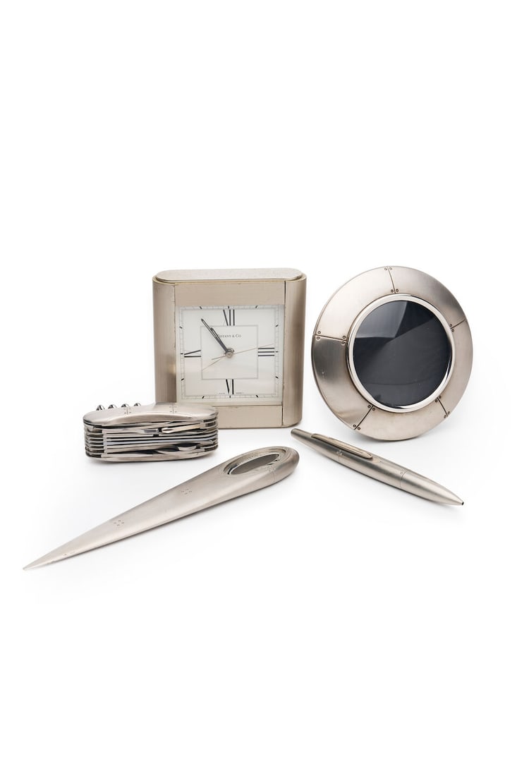 Tiffany & Co. | stainless steel desk accessories (4): Tiffany & Co. | stainless steel desk accessories Comprising a quartz movement table clock, 'Streamamerica' letter opener, pen and army knife. (4) For further information on this lot please visit Bonha