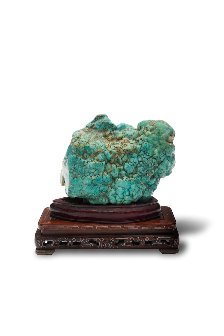 A substantial turquoise specimen: A substantial turquoise specimen of natural form, accompanied by a carved wooden base, weight 3732gm, measuring approx. 18.0 x 15.0cm. For further information on this lot please visit Bonhams.com For 